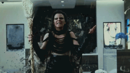 a woman in a witch costume is holding a wand and making a funny face