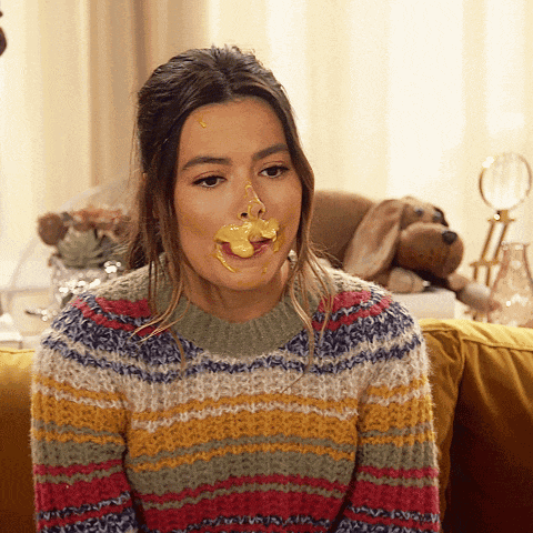 a woman in a striped sweater is sitting on a couch with a yellow substance on her face