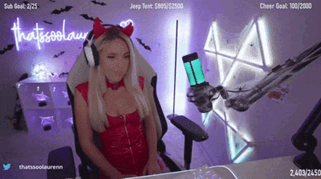 a woman in a devil costume sits in front of a neon sign that says thatsssssshow