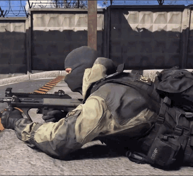 a soldier is laying on the ground with a backpack that says ' sniper ' on the back