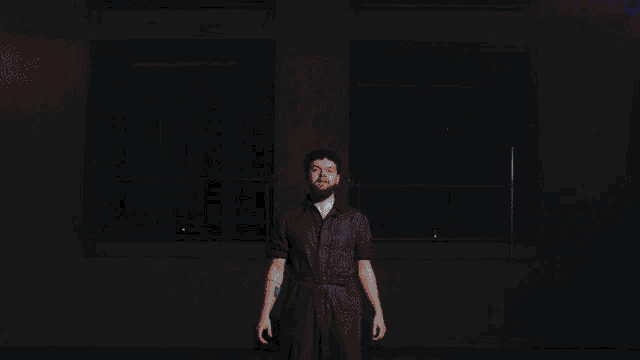 a man with a beard is dancing on a stage in front of a bunch of lights