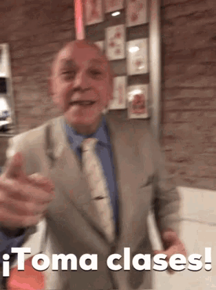 a man in a suit and tie is giving a thumbs up and the words toma clases are below him