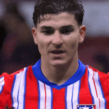 a close up of a man wearing a red and white striped shirt with a blue collar