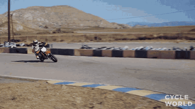 a person riding a dirt bike on a track that says cycle world on the bottom right