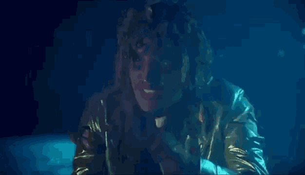 a woman in a gold jacket is talking to a boy in a dark room .