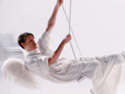 a man with white wings is hanging from a rope
