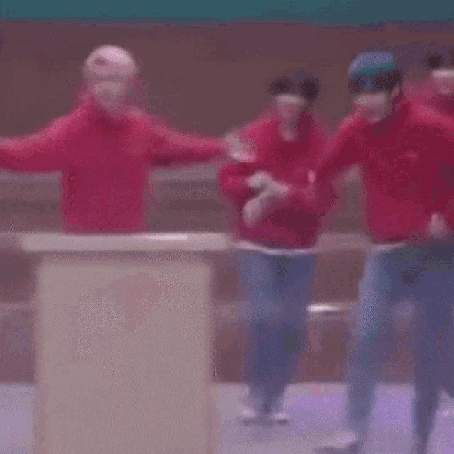 a group of people in red hoodies are dancing together on a stage .