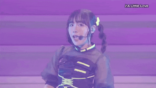a girl is making a heart shape with her fingers while wearing a microphone