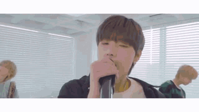 a young man is singing into a microphone in front of a group of people .
