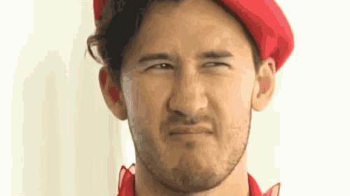 a man with a beard wearing a red hat is making a funny face .