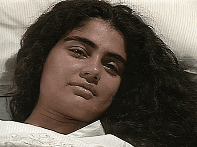 a woman with long hair is laying in a bed