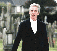 a man in a suit and white shirt is standing in a cemetery .