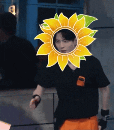 a man wearing a black shirt and orange shorts with a sunflower on his head