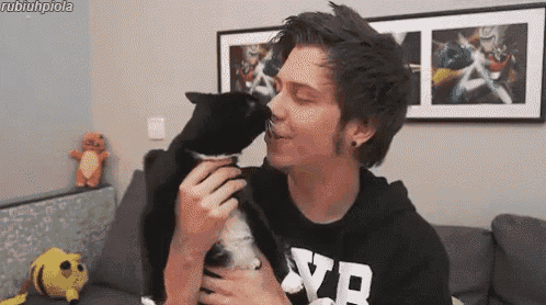 a man in a black shirt with the letter vb on it is holding a black cat .