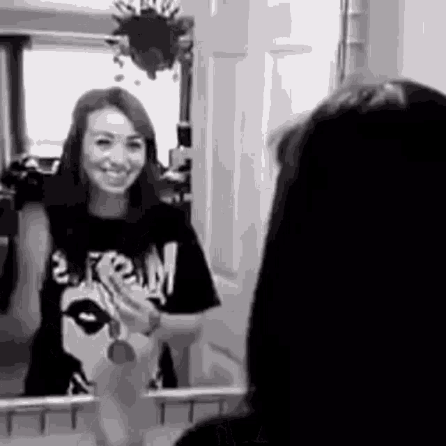 a woman is smiling in front of a mirror while looking at herself .