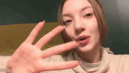 a woman is making a peace sign with her hand and looking at the camera .