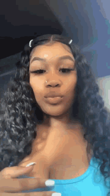 a woman with curly hair and a nose ring is wearing a blue shirt and a blue top .