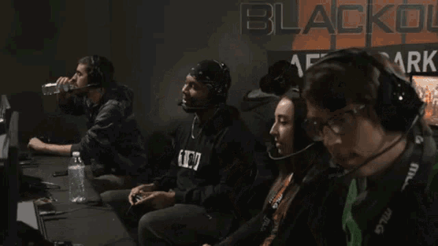 a group of people playing a video game in front of a sign that says blackout