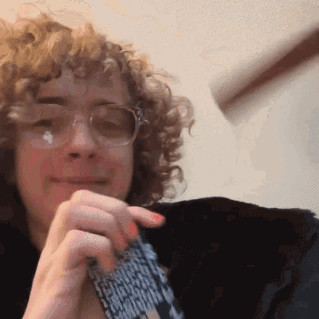 a woman with curly hair wearing glasses and a black jacket