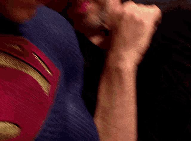 a person in a superman costume is holding another person 's hand