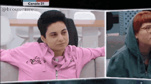 a woman in a pink sweatshirt sits on a couch next to another woman