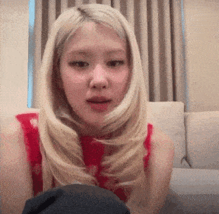 a woman with blonde hair is sitting on a couch in a room .
