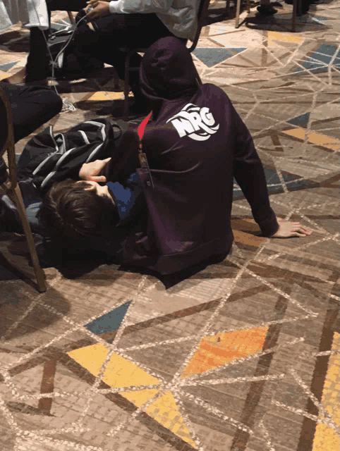 a person wearing a purple nrg hoodie laying on the floor