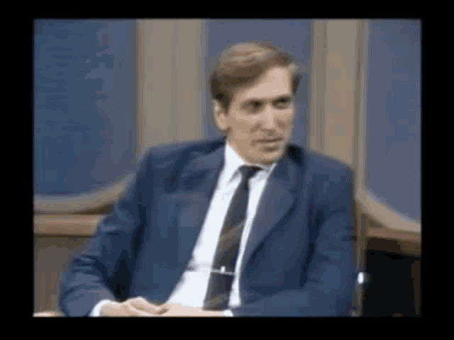 a man in a suit and tie is sitting at a table .