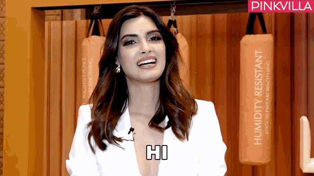 a woman in a white jacket says hi in front of a pinkvilla logo