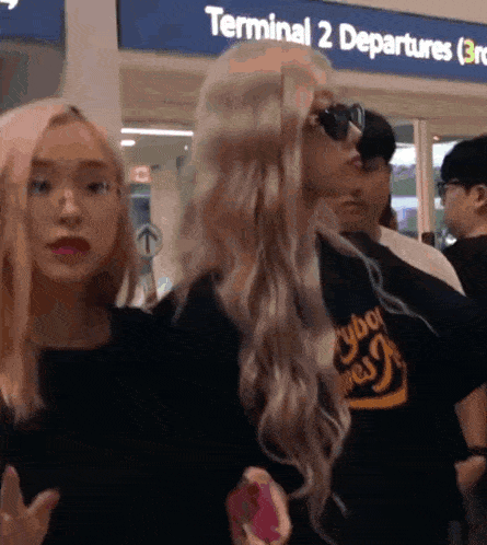 a group of people are standing in front of a terminal 2 departures sign