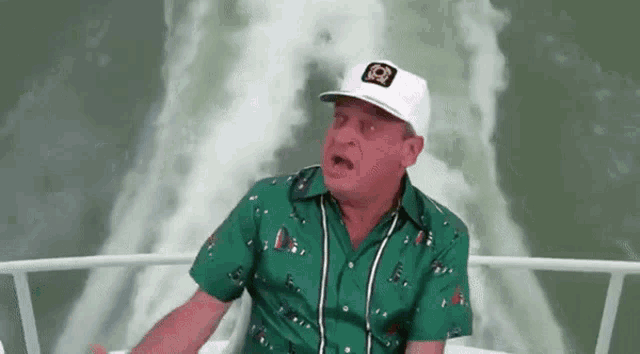 a man in a green shirt and a white hat is sitting on a boat .
