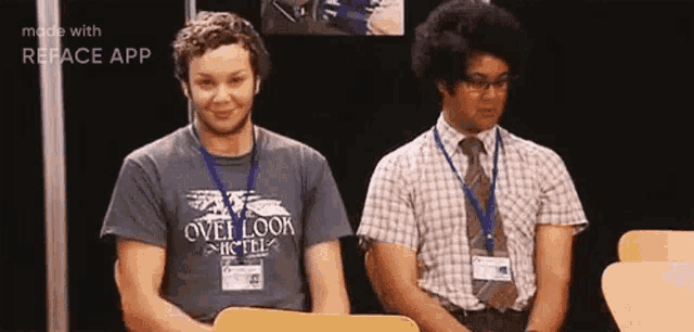 two men are sitting next to each other and one of them is wearing a shirt that says overlook hotel