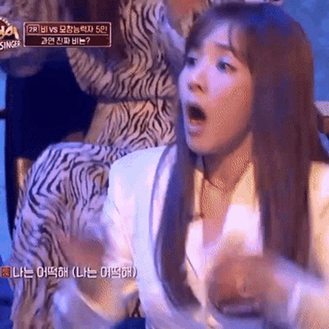 a woman with a surprised look on her face is sitting in a chair .