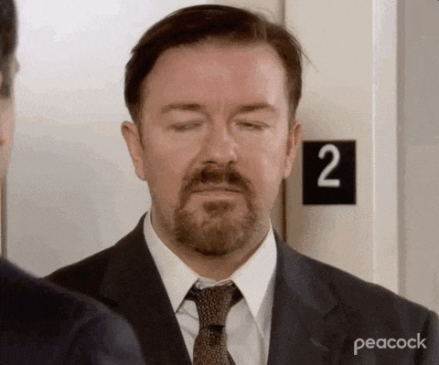 a man with a beard wearing a suit and tie is standing in front of a door with a sign that says 2 .