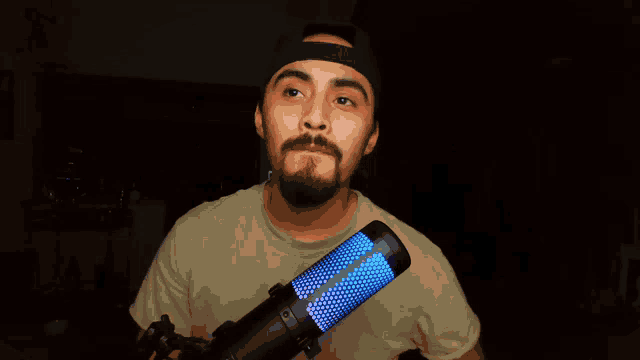 a man with a beard stands in front of a microphone that is lit up