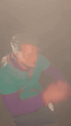 a person wearing a green and purple shirt with a white t on the back