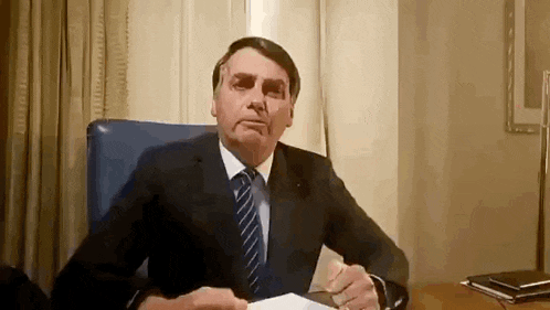 a man in a suit and tie is sitting at a desk with a piece of paper .
