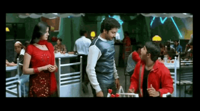 a man in a red jacket is giving a thumbs up to another man in a restaurant