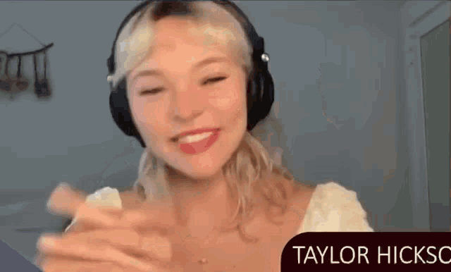 a woman wearing headphones is smiling with the name taylor hicksc below her
