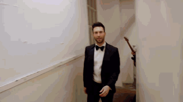 a man in a tuxedo walks down a hallway