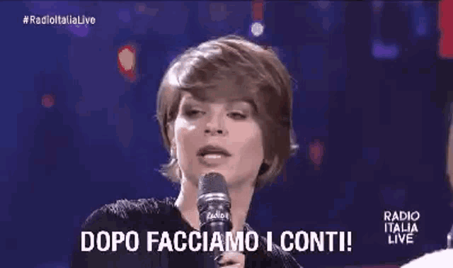 a woman is singing into a microphone on a stage and saying dopo facciamo i conti .