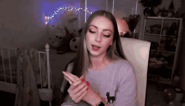 a woman with red nails and a cat on her shirt