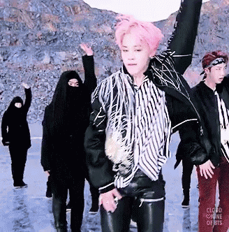 a man with pink hair is dancing with a group of people
