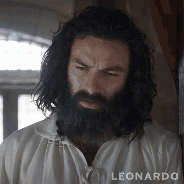 a man with a beard is wearing a white shirt that says leonardo on it
