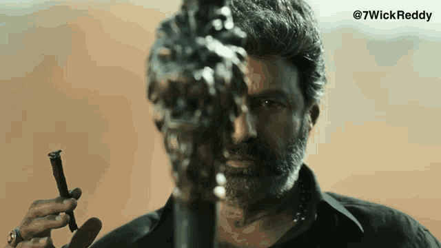 a man with a beard is holding a sword in front of his face and the words @ 7wickreddy are on the bottom right