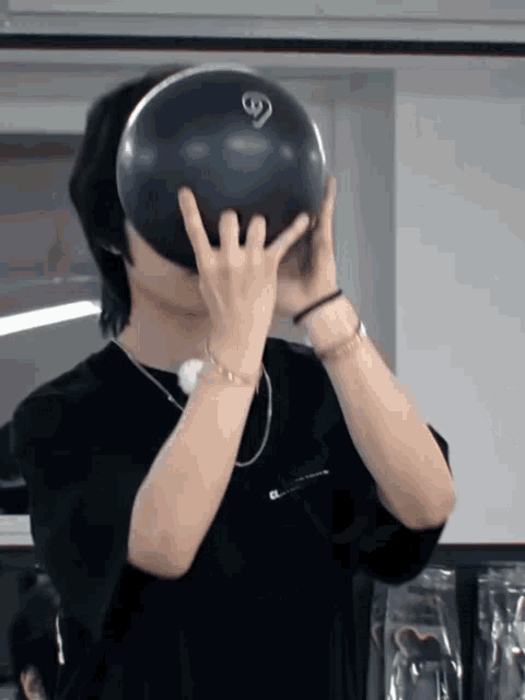 a man holding a bowling ball in front of his face