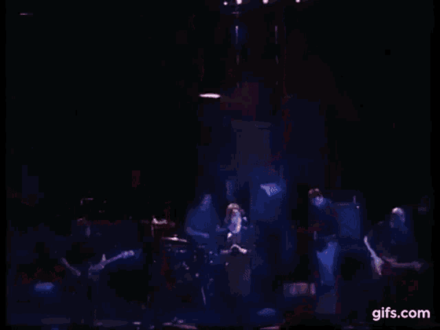 a woman is singing into a microphone on a stage in front of a drum set .