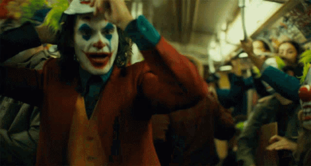 a man in a joker costume is holding a baseball cap over his head