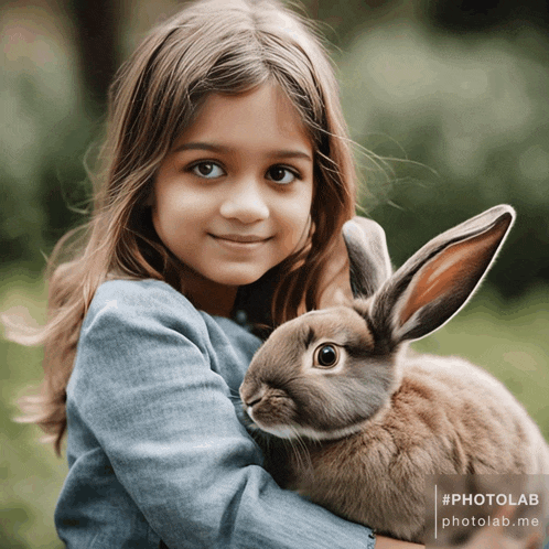 a little girl is holding a brown rabbit in her arms with a photolab watermark