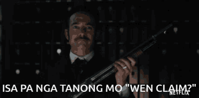 a man in a suit and tie is holding a gun with the caption " isa pa nga tanong mo "